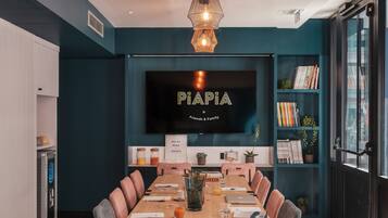 A modern conference room with teal walls, a large flat-screen TV, a wooden table, and comfortable seating.