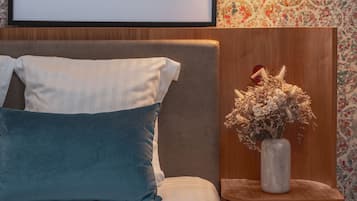 Une affiche encadrée avec l’inscription « PiAPIA Friends & Family » au-dessus d’un lit agrémenté d’oreillers blancs et turquoise.