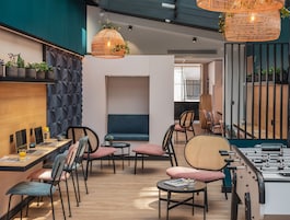 A modern lounge area with seating, tables, and a foosball table.