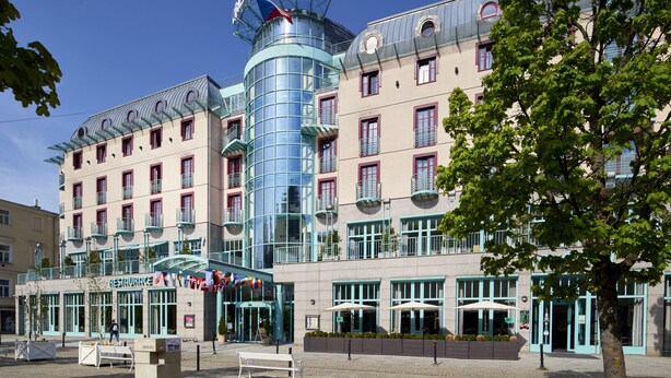 Un hotel con un llamativo letrero que dice "Crystal Palace", con una moderna fachada de vidrio y varios balcones.