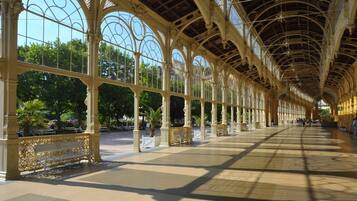 Passadís cobert interior amb arcs ornamentals i bancs, oferint una zona d'ombra per als visitants.