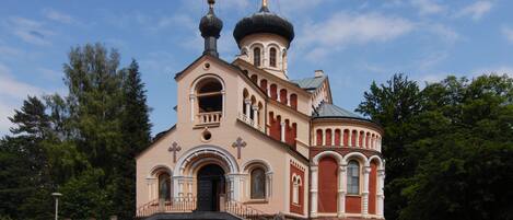 A church with a prominent dome and two crosses on top, surrounded by trees.