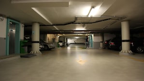 Un garaje de varios niveles con varios automóviles estacionados, pilares de concreto e iluminación colgante.