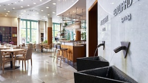 Un moderno vestíbulo de hotel con zona de bar, asientos y una fuente de agua.