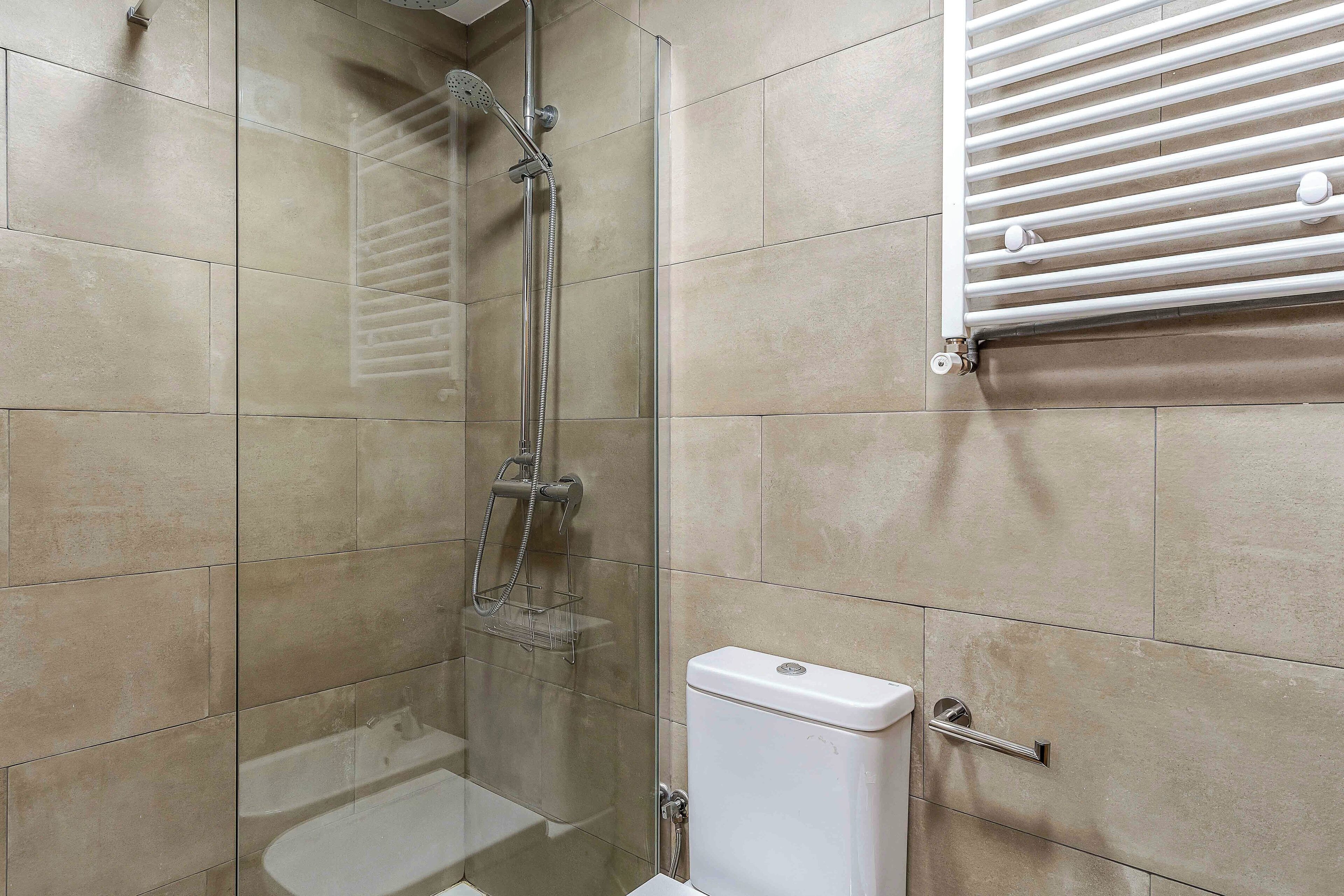 Un baño con ducha de vidrio, inodoro y barra para toallas.
