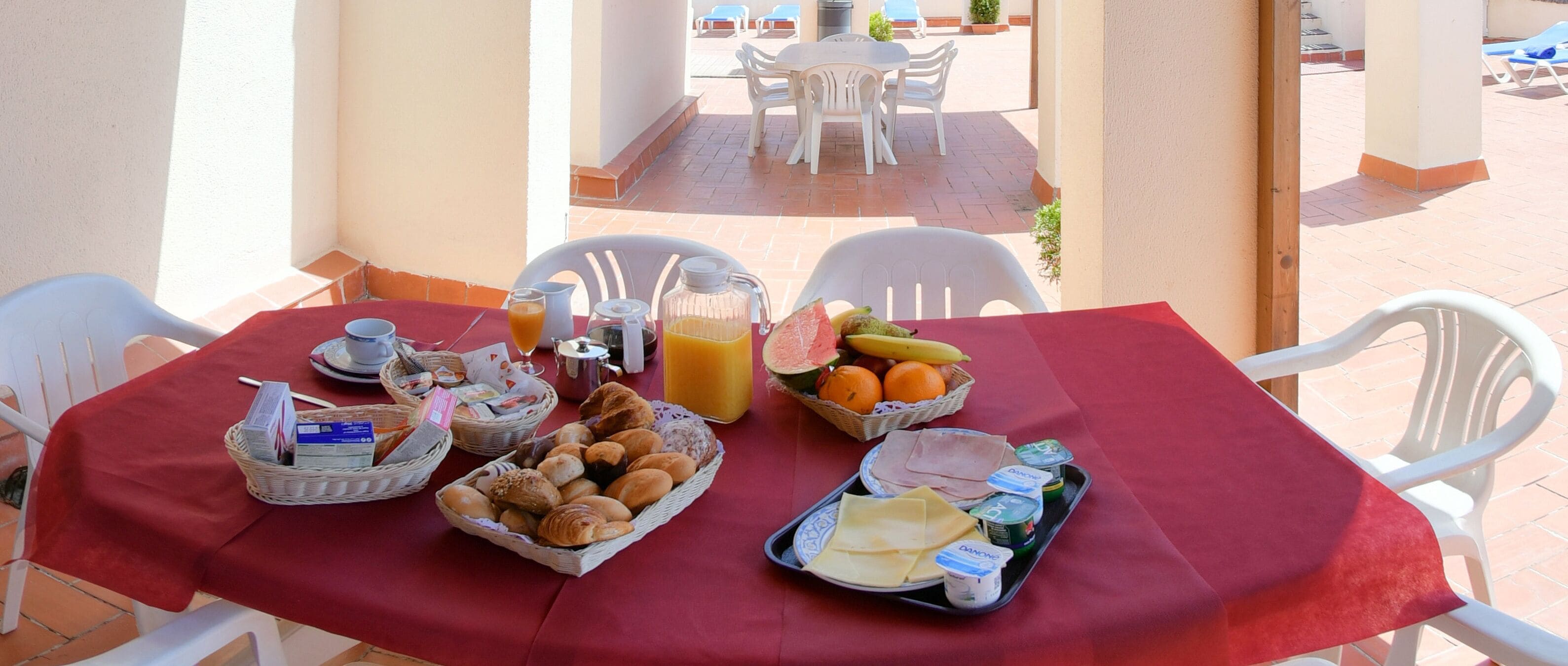 Una mesa de desayuno con diversos alimentos, como pan, frutas y bebidas.