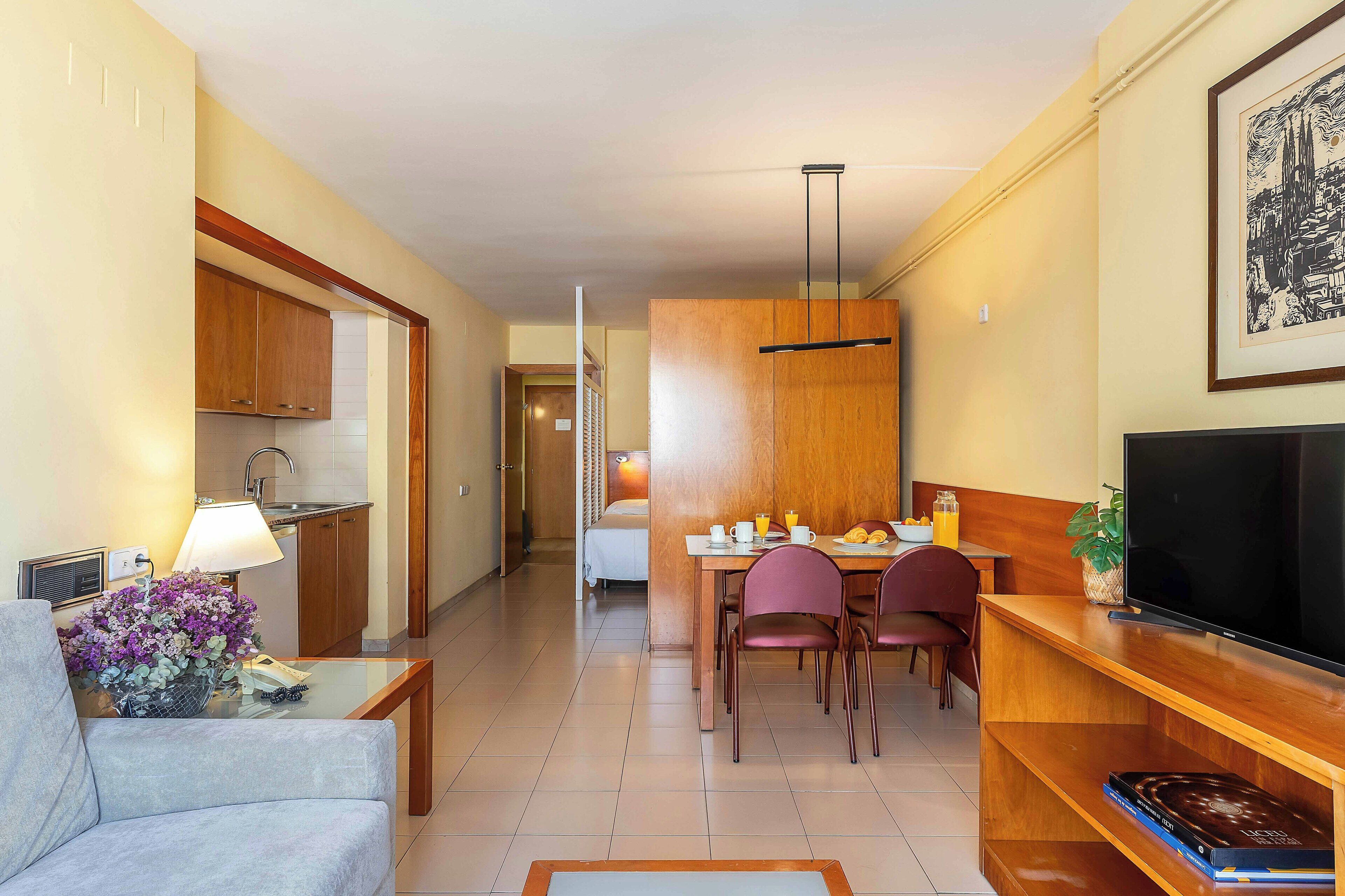Habitación de hotel con comedor, televisión y cama.