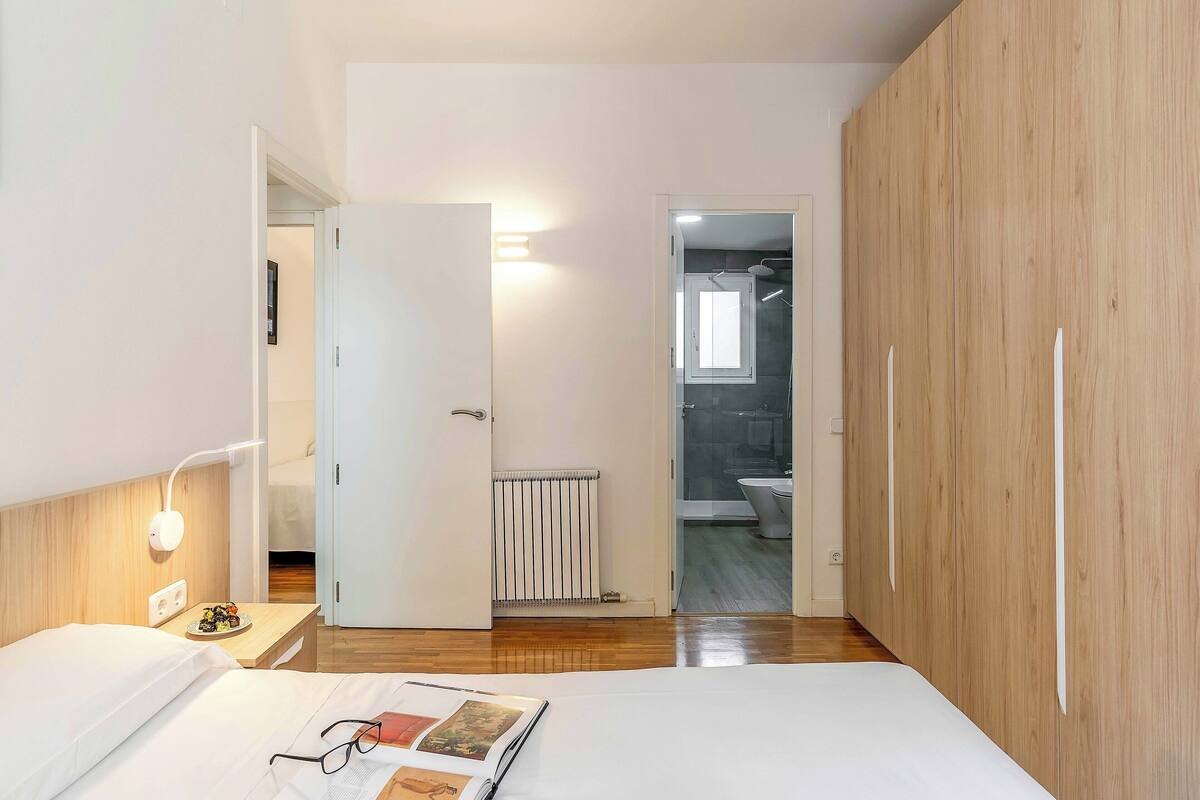 A bedroom with a bed, bedside table, and a view into the bathroom.