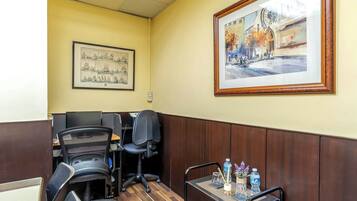 Oficina en esquina con dos sillas, una mesa con una botella de agua y obras de arte enmarcadas en la pared.