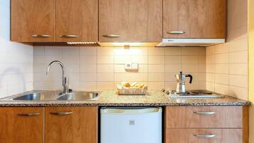 A kitchen with wooden cabinets, a stainless steel sink, a built-in dishwasher, and a coffee maker on the countertop.