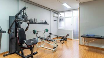 A gym with various exercise equipment, a bench, and a massage table.