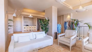 Un moderno vestíbulo de hotel con un sofá blanco, sillas de mimbre, una planta grande y un perchero.