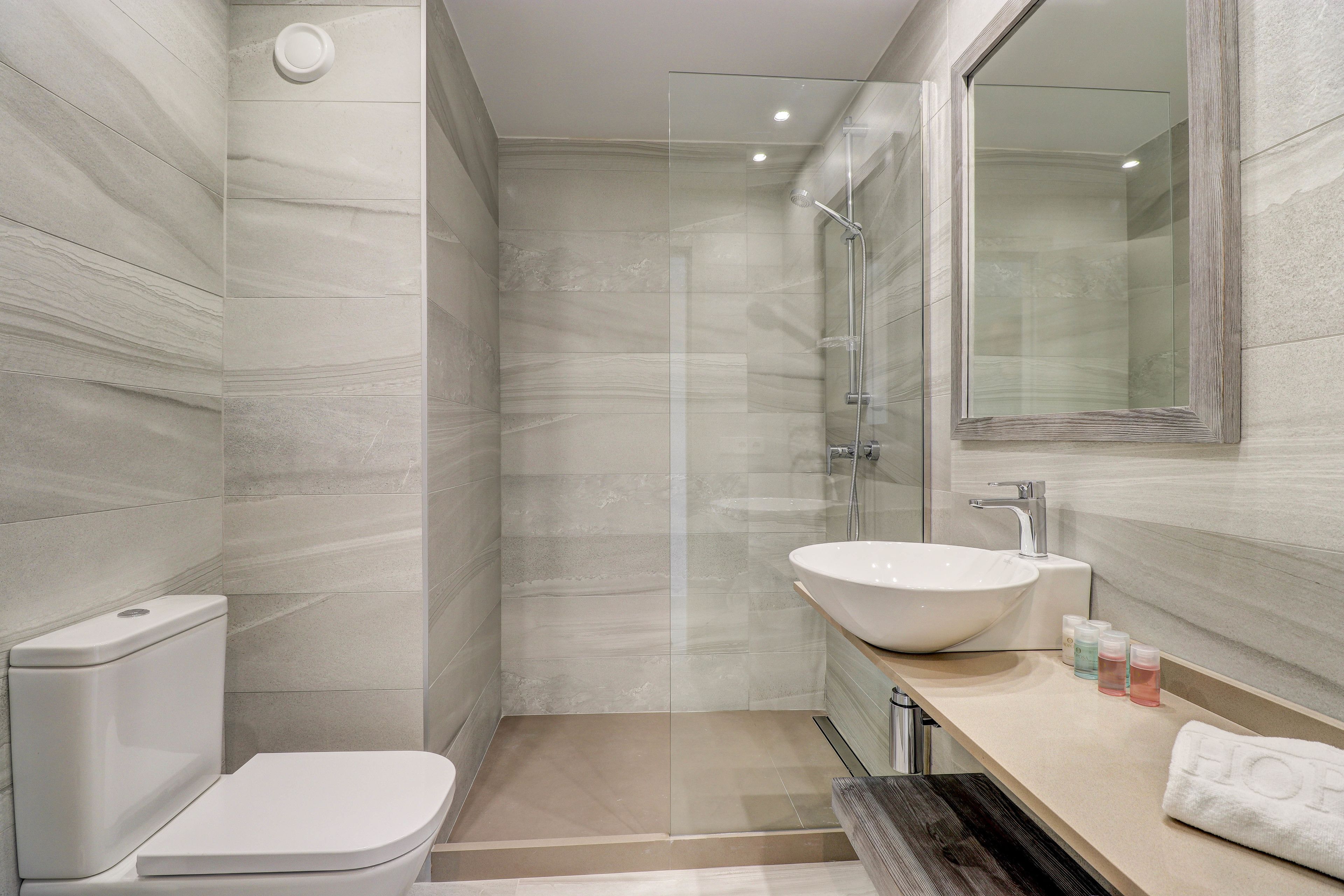 A modern bathroom with a glass-enclosed shower, a white sink, and a toilet.