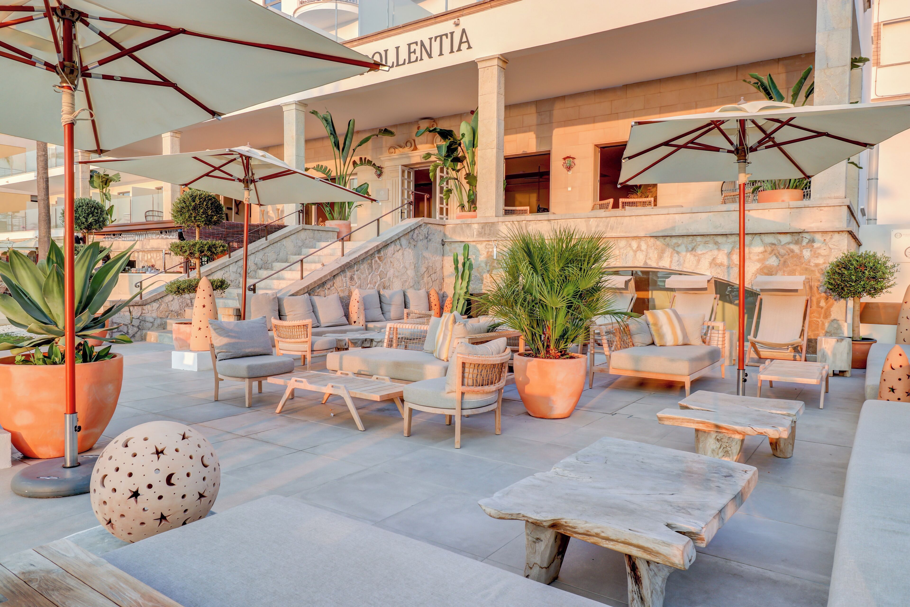A rooftop lounge area with outdoor seating, potted plants, and a staircase leading to an upper level.