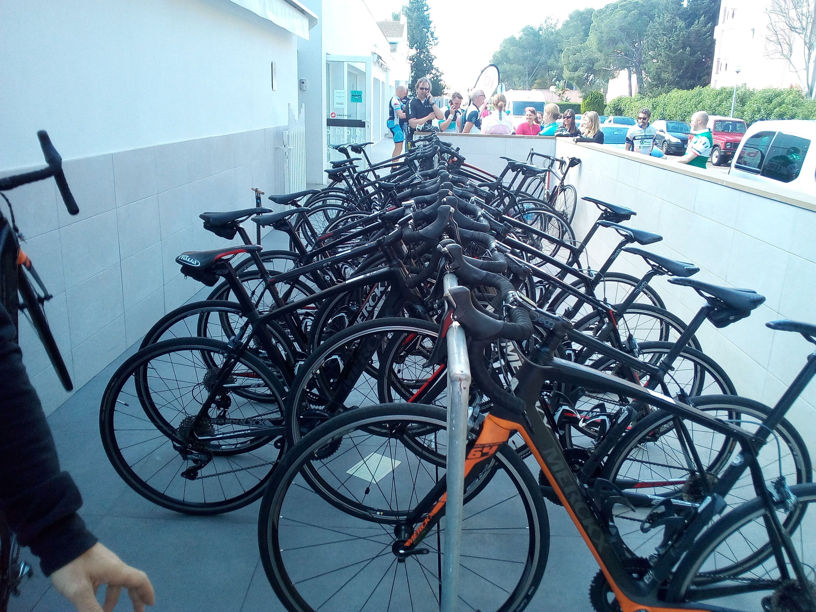 Varias bicicletas estacionadas en un estacionamiento, mientras una persona pasa caminando.