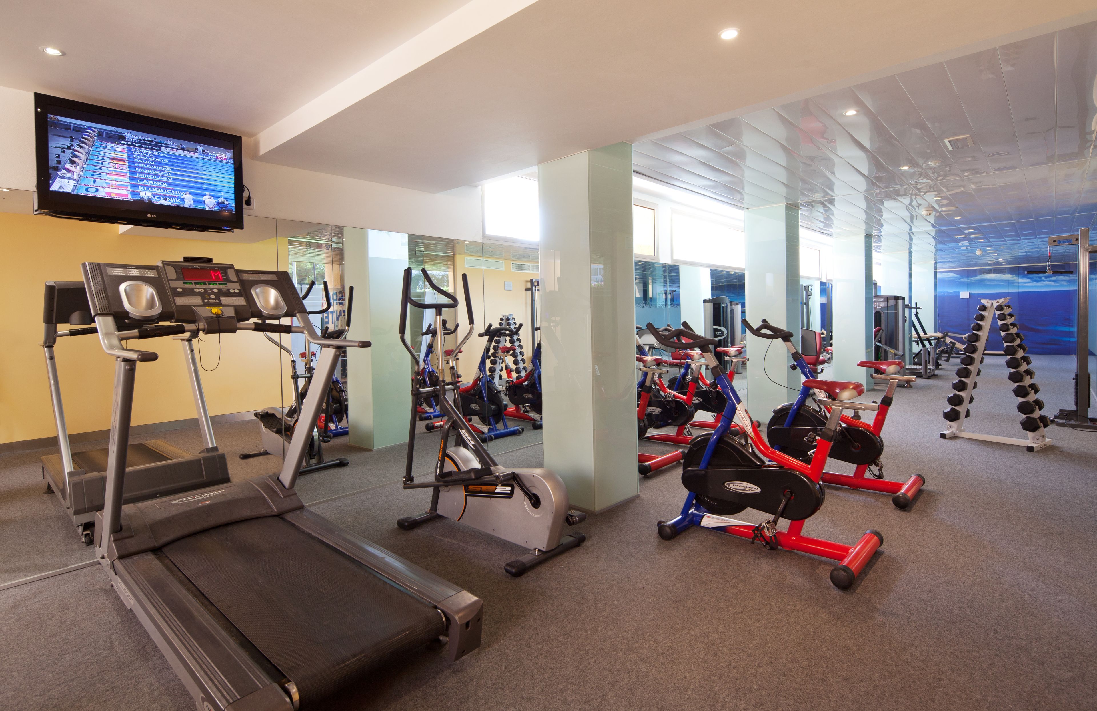 Un gimnasio moderno con cintas de correr, elípticas y máquinas de pesas.