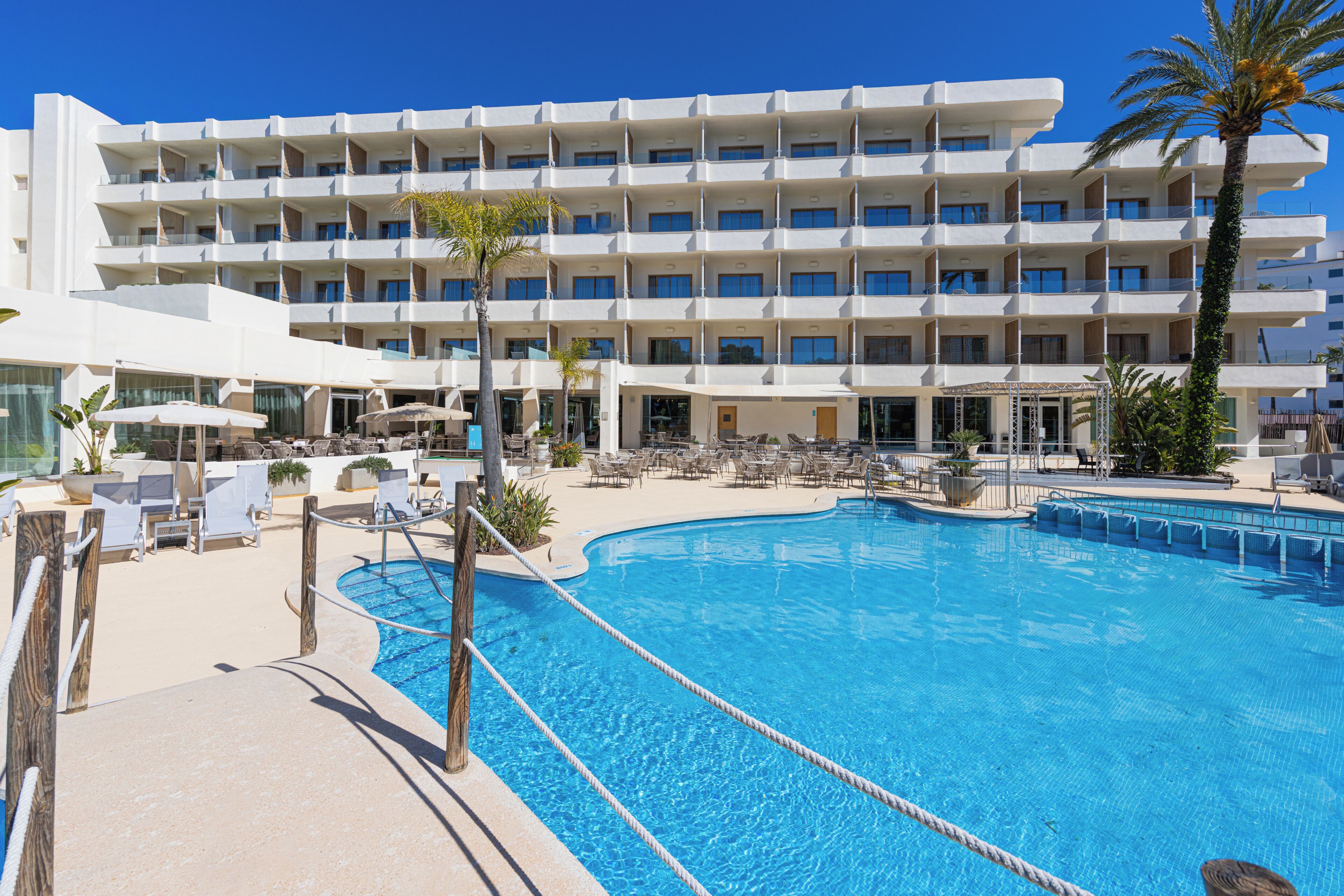 Ein Hotel mit Schwimmbad, mehreren Balkonen und Sitzbereichen im Freien.
