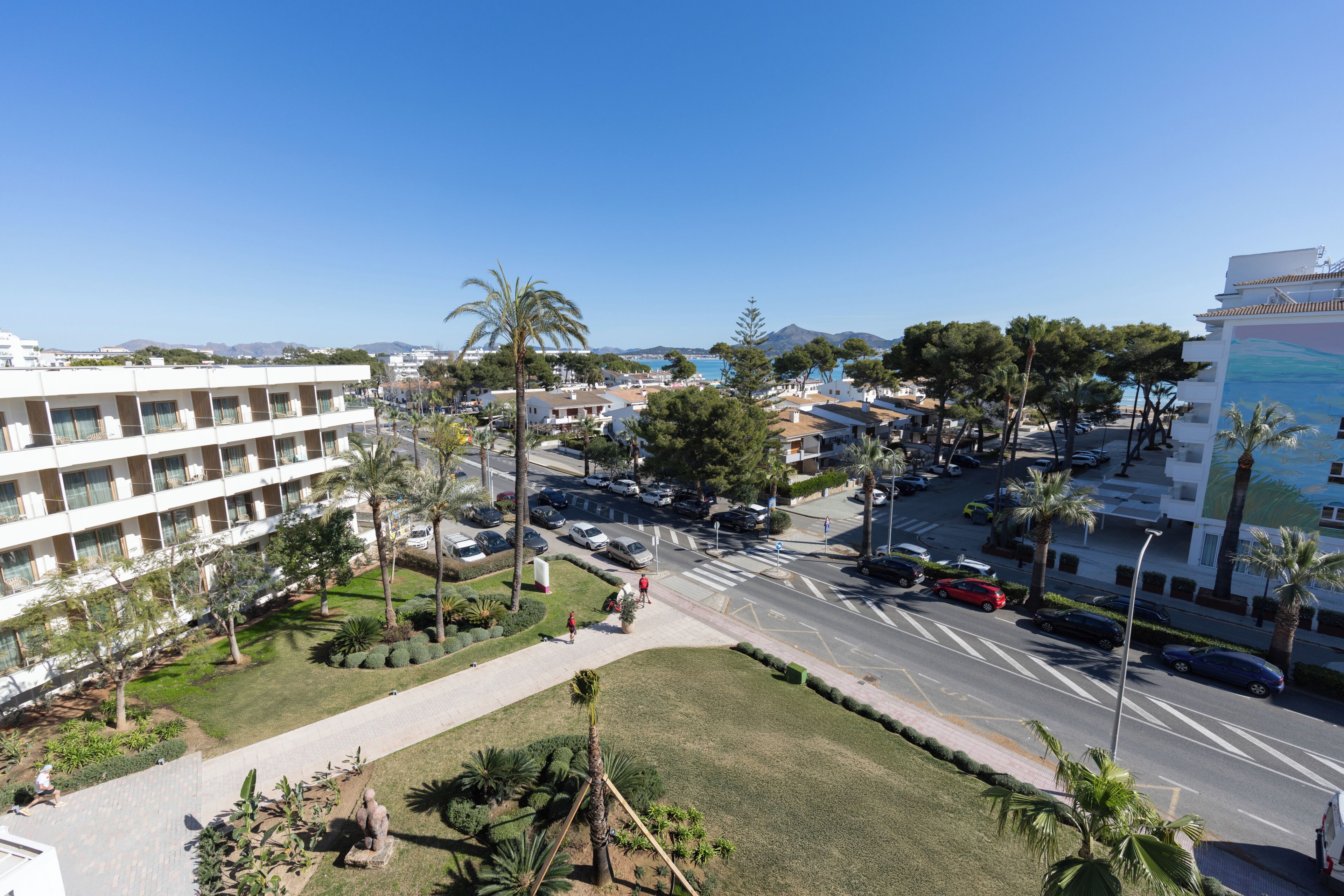 A hotel with multiple floors, a parking lot, and a view of the sea.