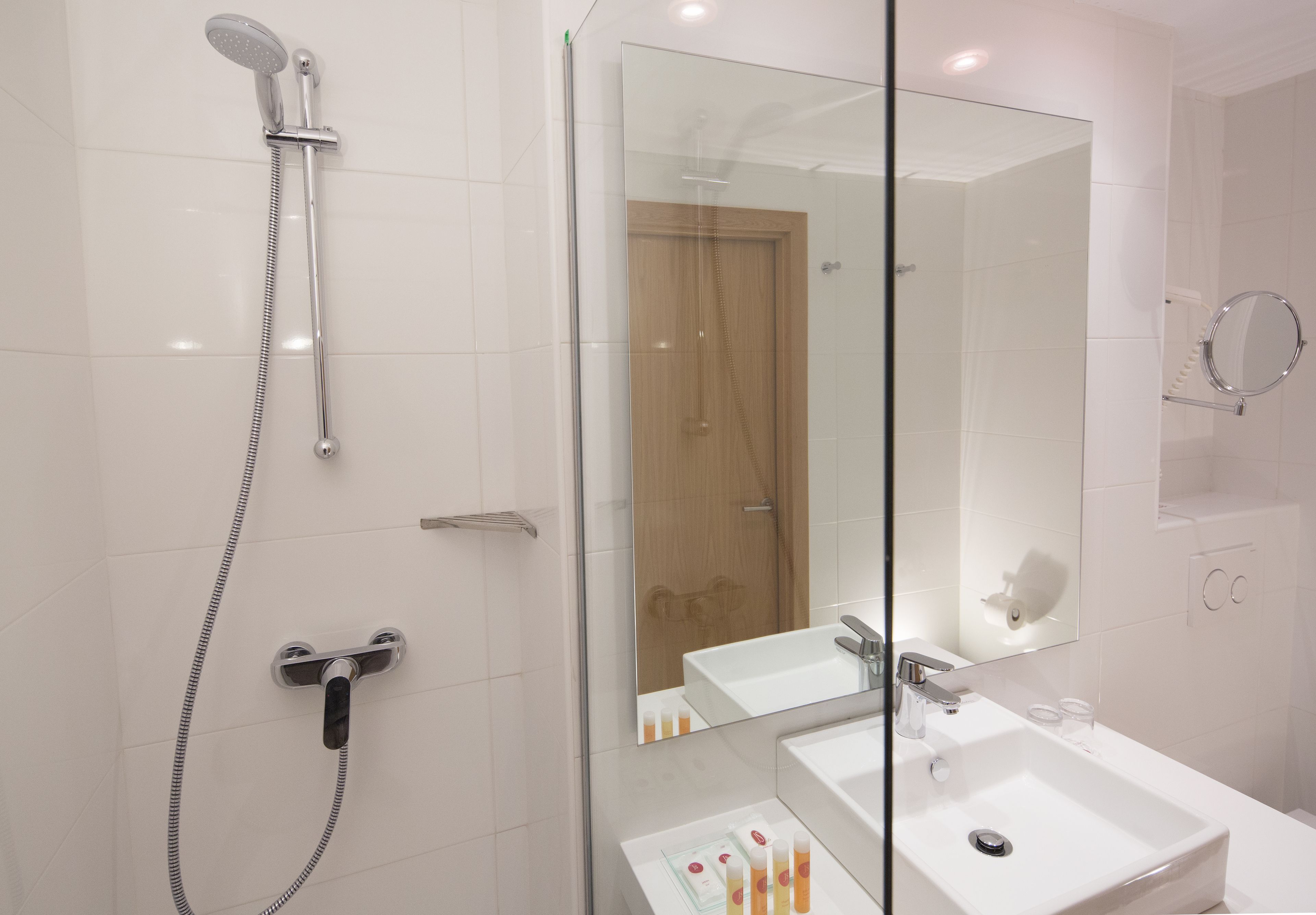 A modern bathroom with a glass shower enclosure, a large mirror, and a white sink.