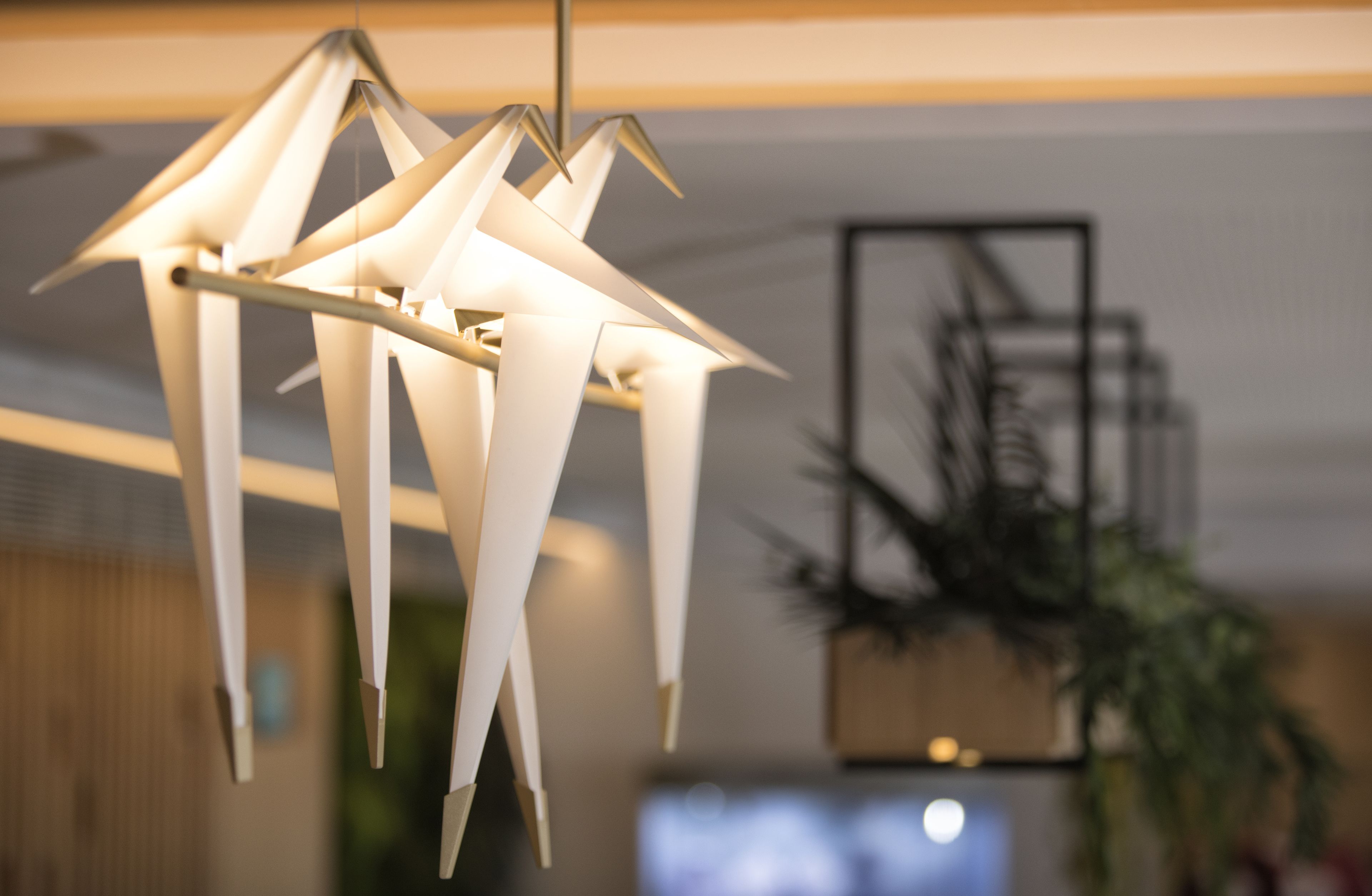 A modern chandelier with geometric shapes and a television in the background.