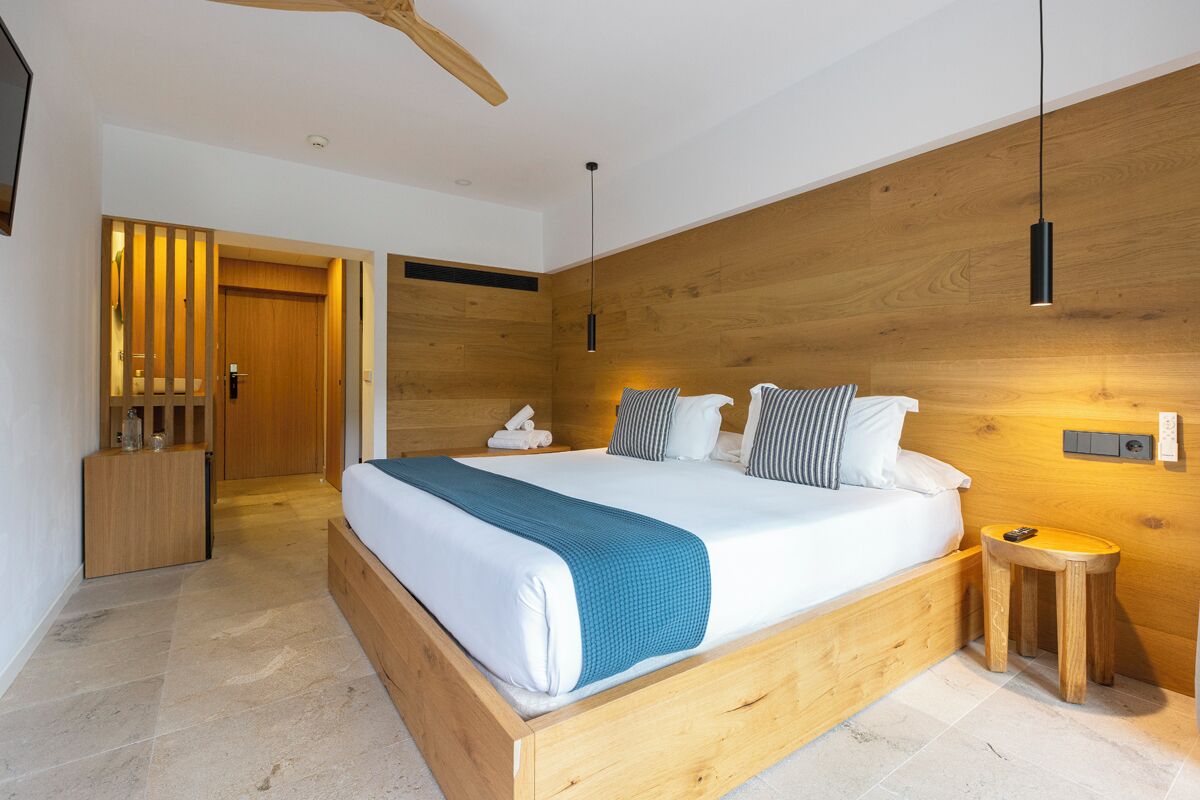 Un dormitorio moderno con una cama de madera, mesitas de noche y un ventilador de techo.