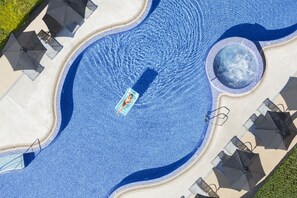 An aerial view of a swimming pool with a central water feature, surrounded by lounge chairs and umbrellas. - Las Gaviotas Suites Hotel (Muro)