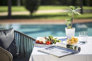 A dining table with a plate of food, a glass of water, and a potted plant. - Las Gaviotas Suites Hotel (Muro)