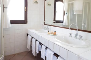 Casa de banho com duas pias, um espelho grande e um porta-toalhas.