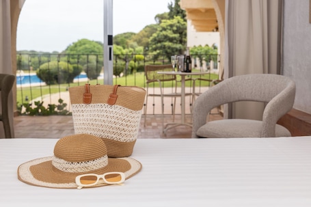A room with a bed, a wicker basket, a straw hat, and sunglasses on the bed.. RVHotels Golf Costa Brava