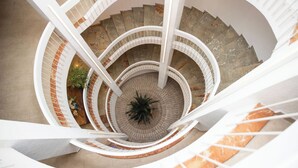 A multi-level spiral staircase with white railings and a central plant. - RVHotels Golf Costa Brava (Santa Cristina de Aro)