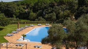 A swimming pool surrounded by lounge chairs and a well-maintained garden. - RVHotels Golf Costa Brava (Santa Cristina de Aro)