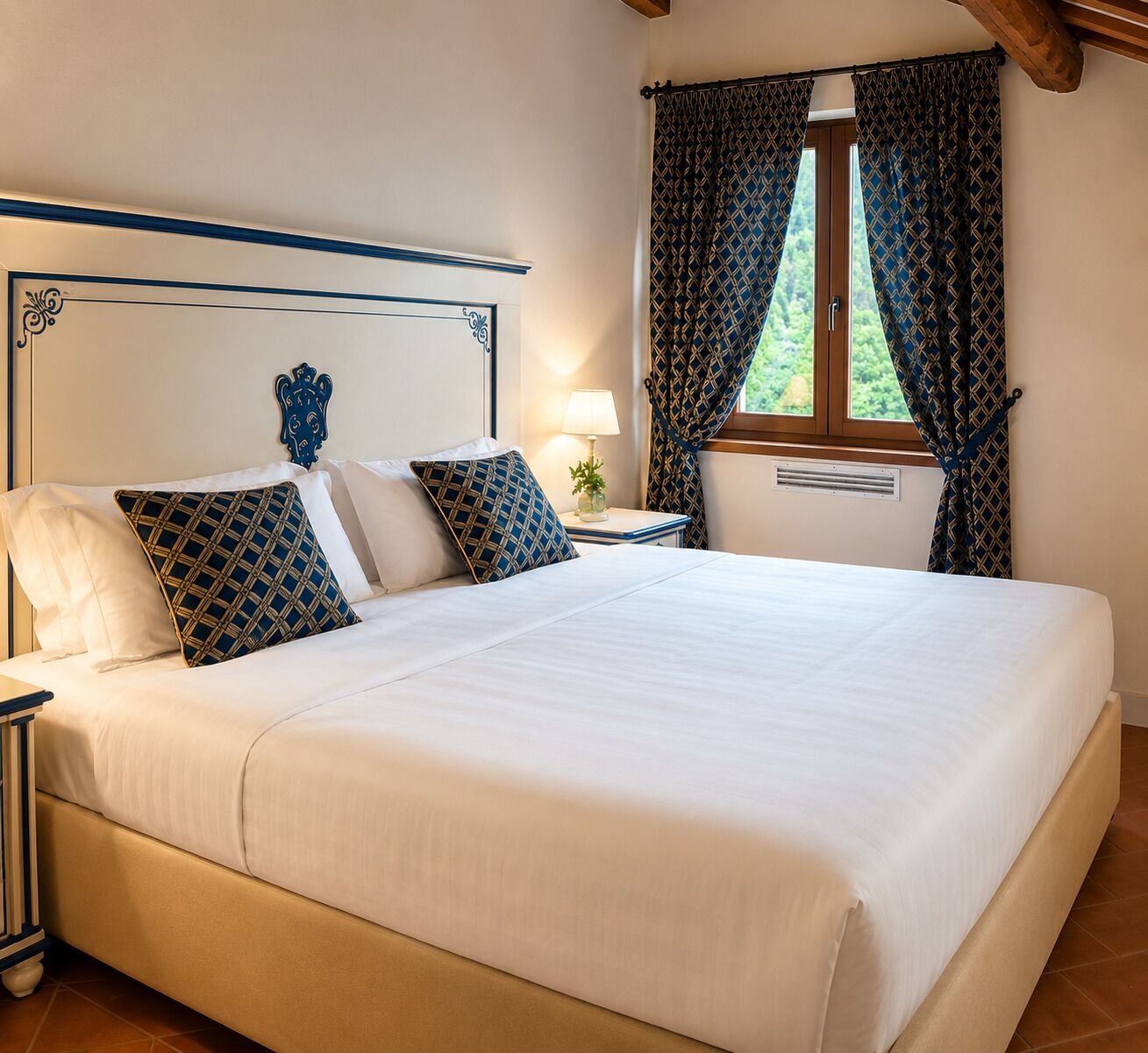 A neatly made bed with a headboard, a bedside table with a lamp, and a window with curtains.