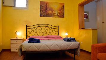 A bedroom with a bed, bedside lamps, a nightstand, a chair, a painting on the wall, and a window.