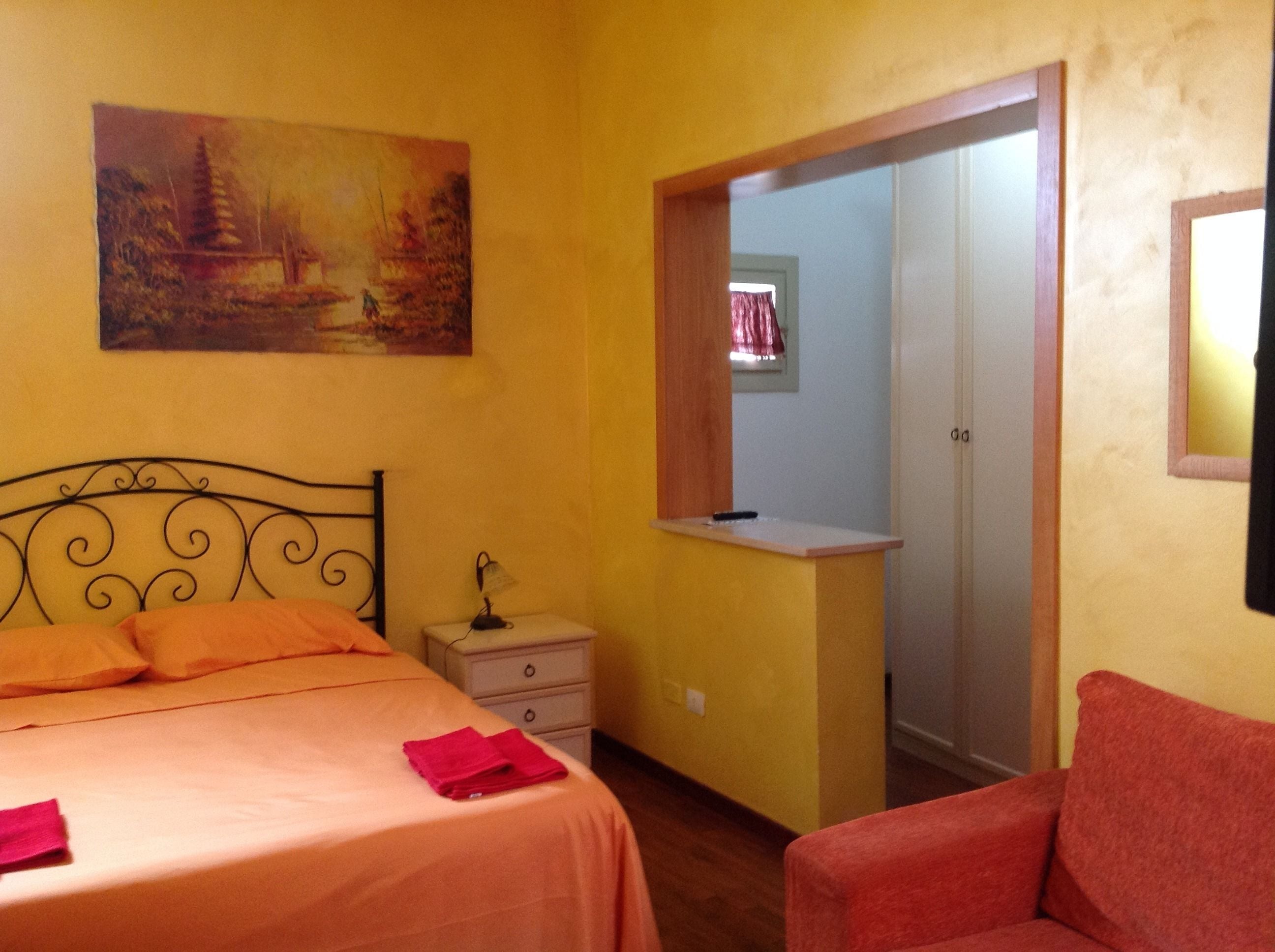 Une chambre à coucher comprenant un lit, une table de chevet, un bureau, une chaise, un tableau accroché au mur et une armoire.