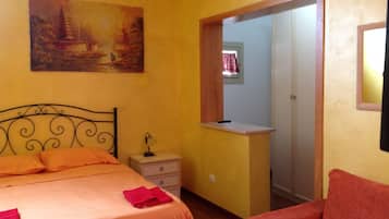 Una camera da letto con un letto, un comodino, una scrivania, una sedia, un quadro appeso al muro e un armadio.