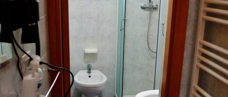 A bathroom with a sink, bidet, and shower.