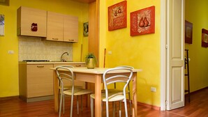 A compact kitchen with wooden cabinets, a dining table, and chairs. - La Corte Bed & Breakfast (Lecce)