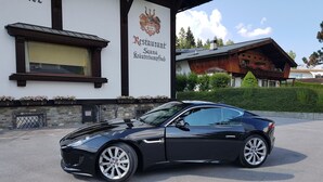 A black sports car parked in front of a building with a sign that reads "Restaurant Sauna Kräuterdampfbad". - Vergeiner (Seefeld in Tirol)