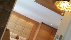 A modern hotel room with a wooden ceiling, a plush sofa, a small bed, and a wooden floor. - Vergeiner (Seefeld in Tirol)