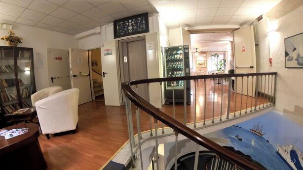 Un hall d’hôtel avec un escalier, un comptoir d’accueil et un espace repas.