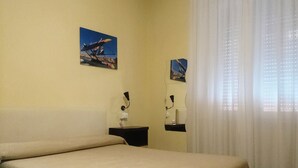 Une chambre d’hôtel comprenant un lit, une table de chevet, un miroir et deux tableaux accrochés au mur.