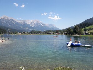 A clear lake with boats, a dock, and mountains in the background. - Landhaus Charlotte (Seefeld in Tirol)