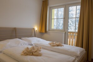 A hotel room with two beds, a window with curtains, and a view of snow-covered trees. - Landhaus Charlotte (Seefeld in Tirol)
