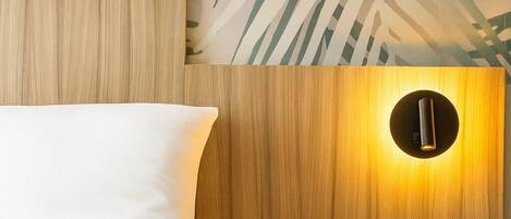 A bedroom with a wooden headboard, a white bed, and a nightstand with a circular light fixture.