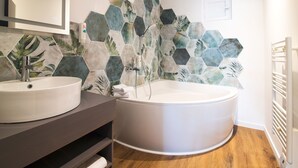 Een badkamer met een rond bad, twee wasbakken en een spiegel.