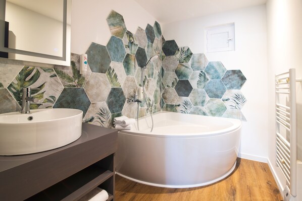 A bathroom with a round bathtub, two sinks, and a mirror.