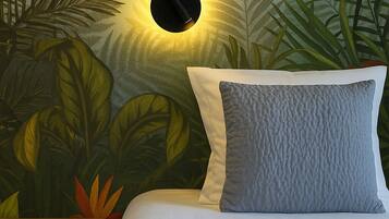 A bedroom with a bed, a nightstand, and a wall mural of tropical foliage.