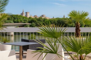 A terrace with outdoor seating, a view of a historic cityscape, and a body of water.