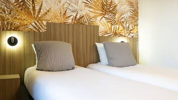 A double bed with a wooden headboard and two bedside tables, each with a wall-mounted light.