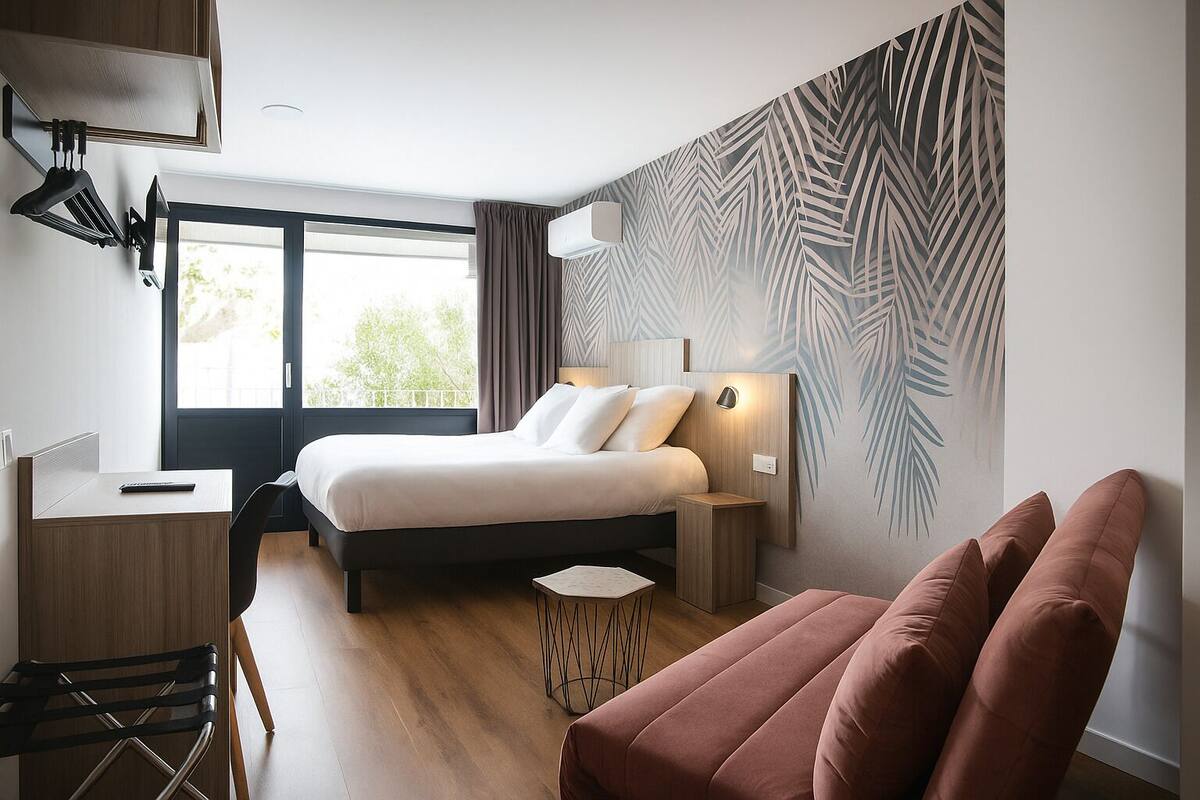 A modern hotel room with a bed, a desk, a chair, a small table, and a sofa.